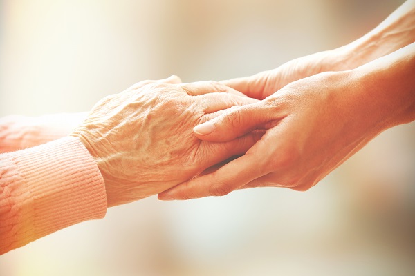 Younger pair of hands holding older persons hands