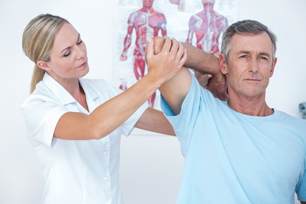 Woman physiotherapist treating a mans shoulder