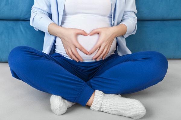 Pregnant woman with hands in a heart over her bump